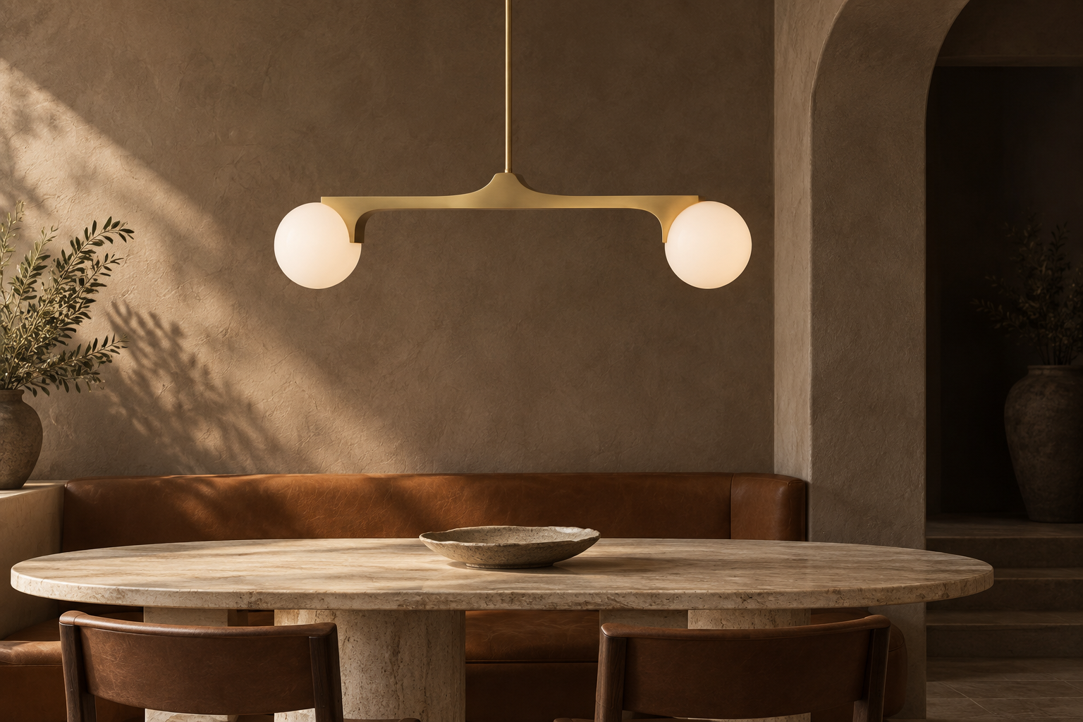 Briar linear pendant above an oval travertine dining table in a warm plaster alcove