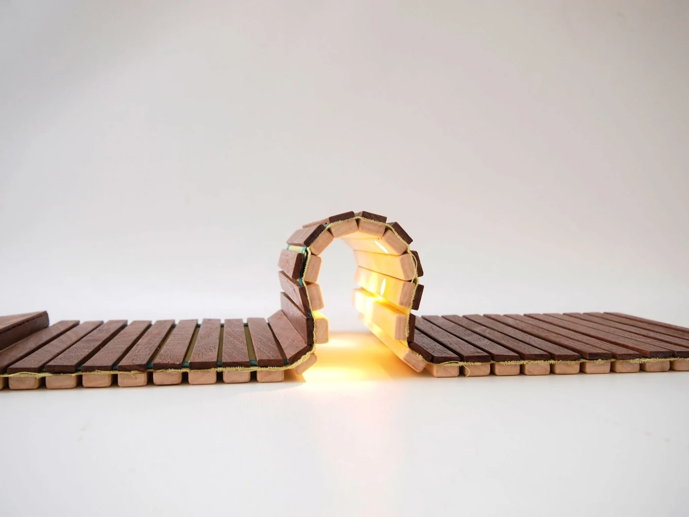 The same wooden lighting project curved into a loop with warm light inside